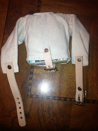  We design and manufacture straight jackets.  We make straight jackets for many different types of people from magicians and escape artist to people that just want an unusual Halloween costume. Now you can own an original Monkey Dungeon straight jacket.  This jacket fits a deck of cards so it's great for magician's that want a neat package for their cards or want to introduce the card trick as a houdini trick.  It can also be used to hang from your rear view mirror. They make a great gift for Houdini and magic fans. Whatever you get it for you will be pleased with the quality and marvel at it's tiny size.
Made with the same high quality materials that our full size jackets are made with including industrial rivets, heavy duty canvas, metal buckles and genuine leather straps.